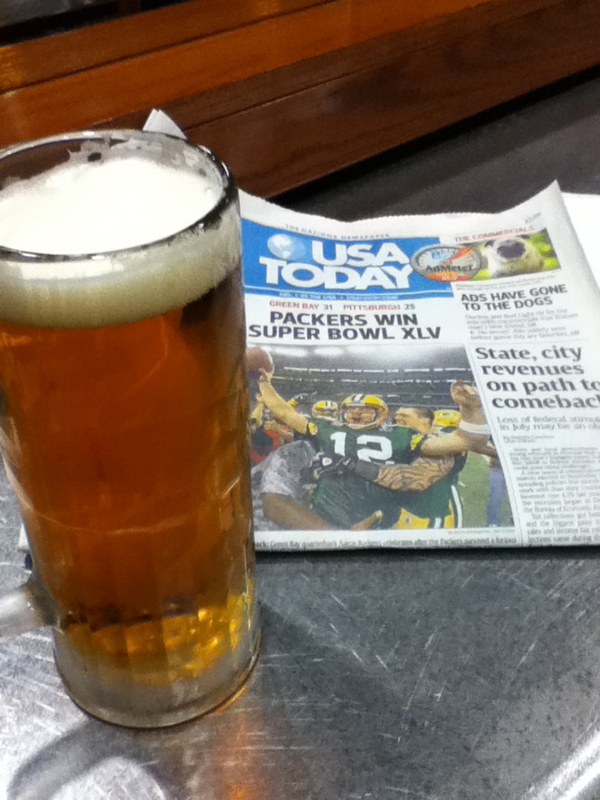 スーパーボウルの結果を報じる新聞を見ながらビールを